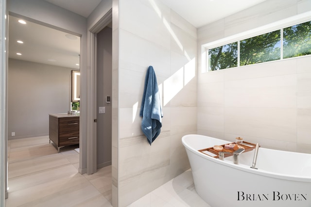 bathroom featuring vanity, a bathtub, and tile walls