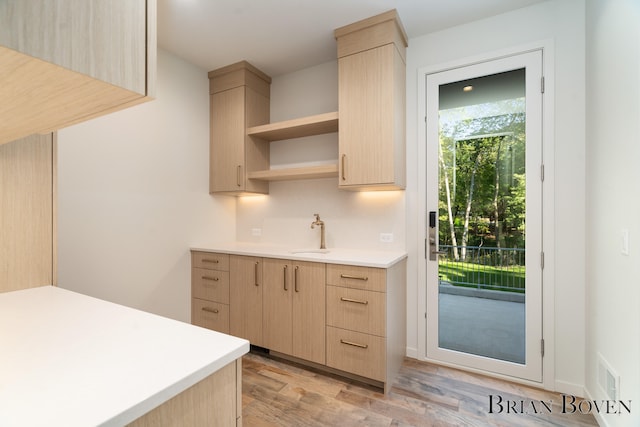 kitchen with light brown cabinets, light hardwood / wood-style floors, and sink