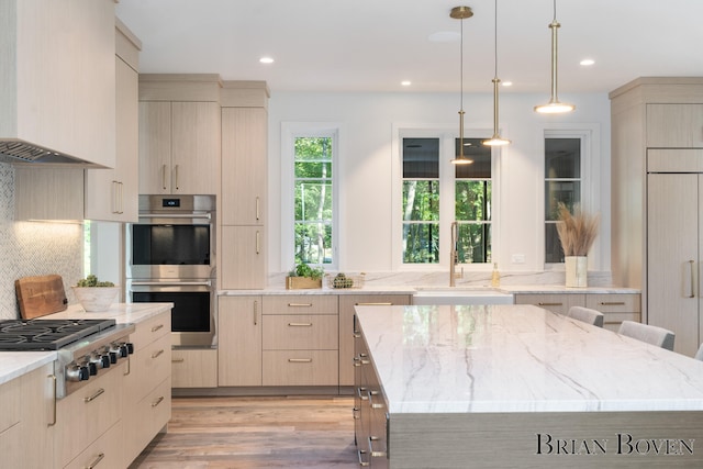 kitchen with appliances with stainless steel finishes, light brown cabinets, a kitchen island, and sink