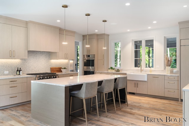 kitchen featuring sink, a kitchen island, light hardwood / wood-style floors, kitchen peninsula, and stainless steel appliances