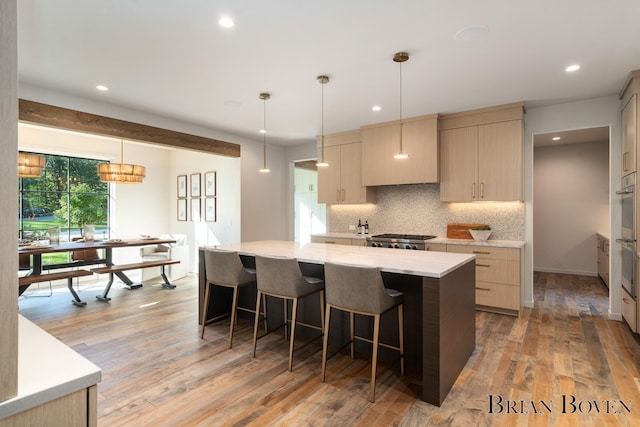 kitchen featuring a center island, hanging light fixtures, light brown cabinetry, tasteful backsplash, and light hardwood / wood-style floors