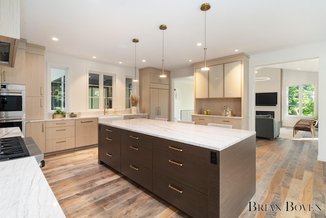 kitchen with light stone countertops, light hardwood / wood-style flooring, double oven, backsplash, and pendant lighting