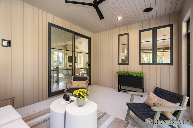 sitting room featuring ceiling fan and wood walls