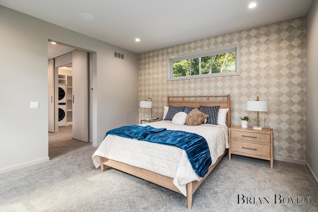 carpeted bedroom featuring stacked washer and clothes dryer