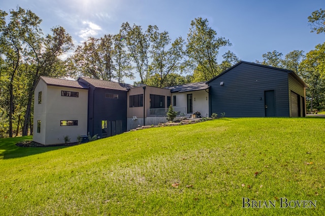 rear view of property with a sunroom, a garage, and a lawn