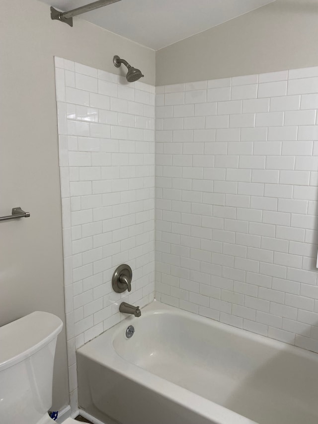 bathroom with tiled shower / bath combo and toilet