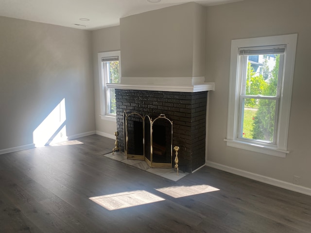 unfurnished living room featuring a fireplace, dark hardwood / wood-style flooring, and plenty of natural light