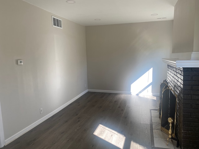 unfurnished living room featuring dark wood-type flooring and a brick fireplace