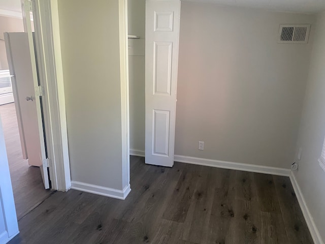 unfurnished bedroom featuring a closet and dark wood-type flooring