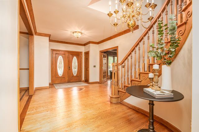 foyer with crown molding, a notable chandelier, and light wood-type flooring