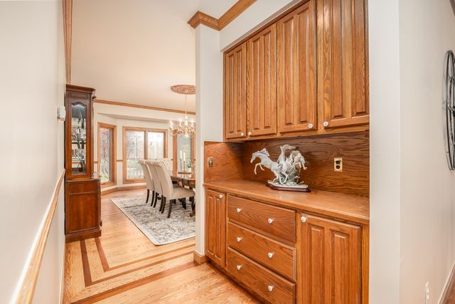 kitchen with decorative backsplash, light hardwood / wood-style flooring, a notable chandelier, and ornamental molding