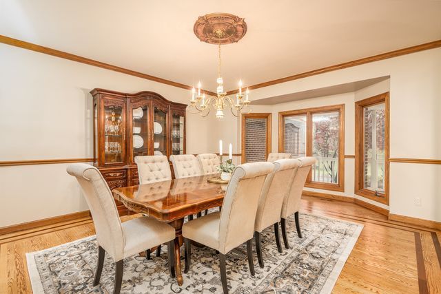 dining room with crown molding, light hardwood / wood-style flooring, and a notable chandelier