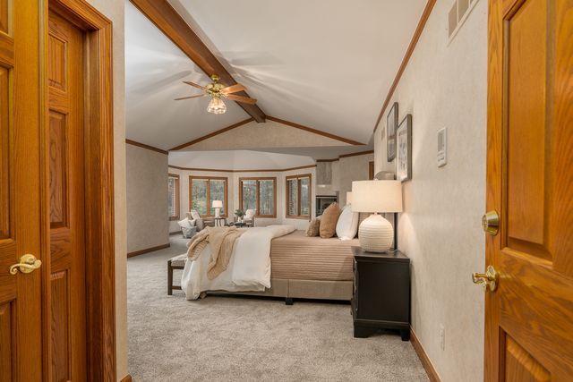 bedroom with lofted ceiling with beams, light colored carpet, ceiling fan, and ornamental molding