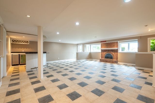 unfurnished living room with ornamental molding, a healthy amount of sunlight, indoor bar, and a brick fireplace