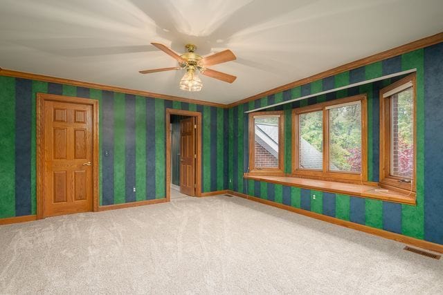 carpeted spare room with ceiling fan and crown molding