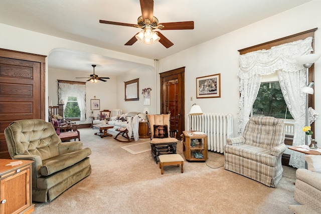 living room featuring ceiling fan, radiator heating unit, and light carpet