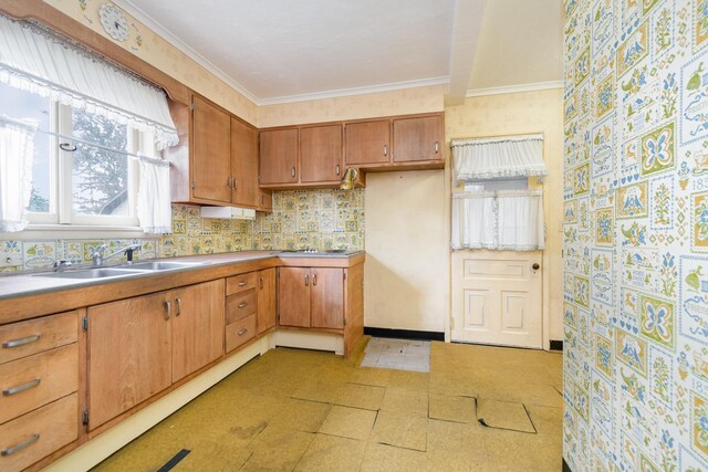 207 N Pine River St, Ithaca, MI 48847 - kitchen with light flooring, wallpapered walls, a sink, brown cabinets, and ornamental molding
