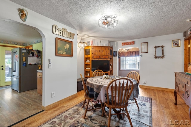 dining space with a textured ceiling, light wood-type flooring, and a healthy amount of sunlight