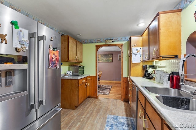 kitchen with decorative backsplash, sink, light wood-type flooring, and stainless steel appliances