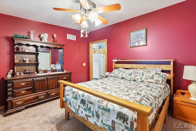 carpeted bedroom featuring ceiling fan, a textured ceiling, and white refrigerator