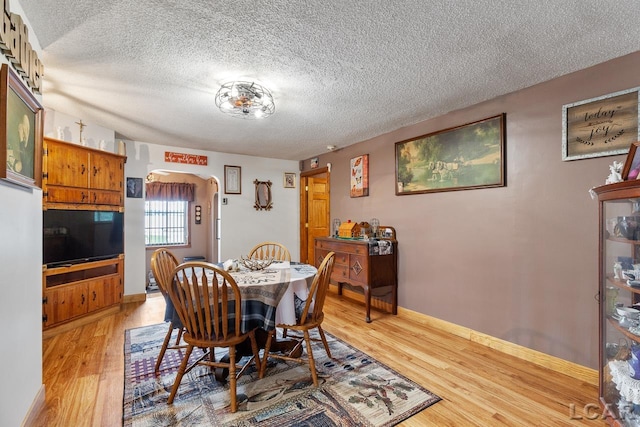 dining room with a textured ceiling and light wood-type flooring