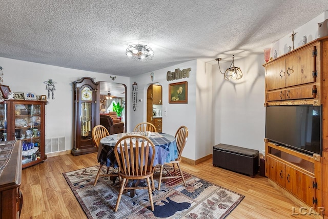 dining room with light hardwood / wood-style flooring and a textured ceiling