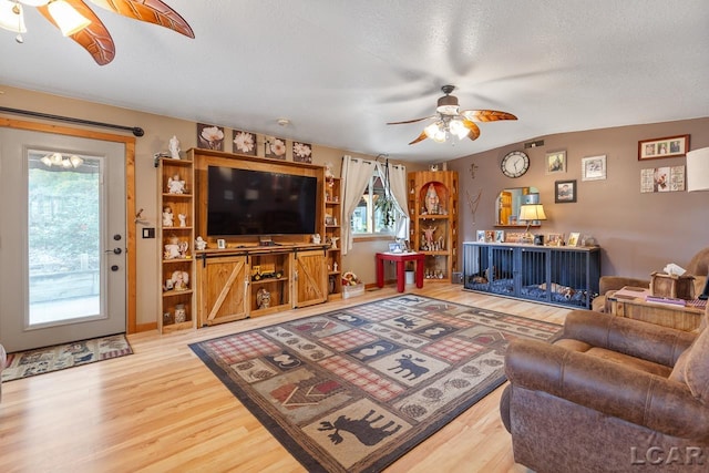 living room featuring a textured ceiling, hardwood / wood-style flooring, ceiling fan, and lofted ceiling