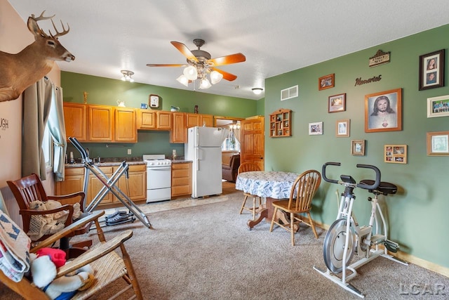 kitchen with a textured ceiling, ceiling fan, light colored carpet, and white appliances