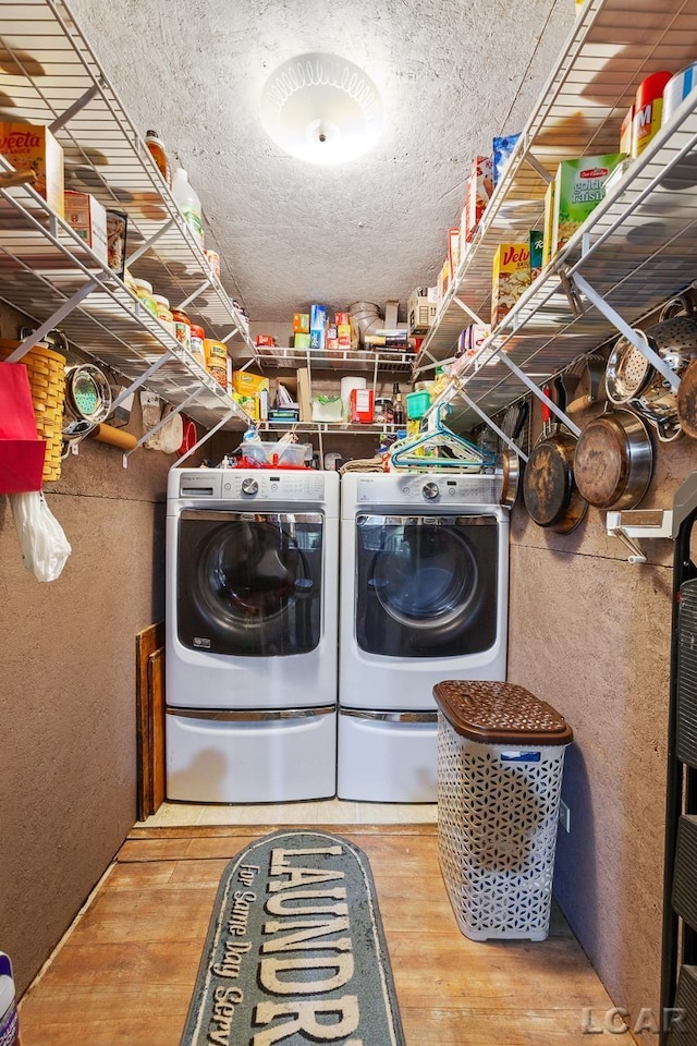 laundry room featuring washing machine and clothes dryer and hardwood / wood-style floors