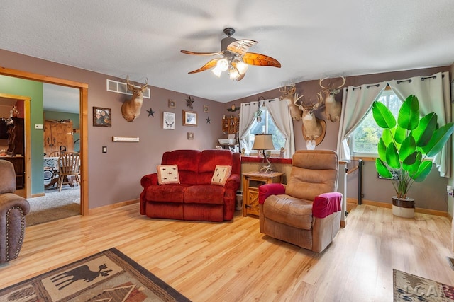 living room featuring ceiling fan, hardwood / wood-style floors, and a textured ceiling