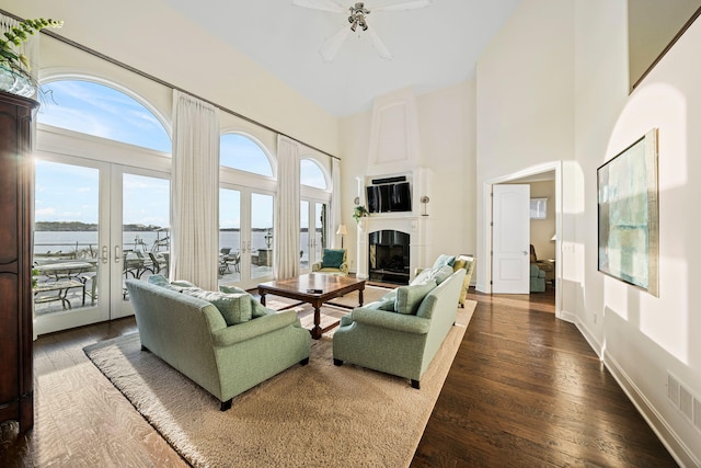 living area with visible vents, hardwood / wood-style floors, french doors, a fireplace, and a towering ceiling