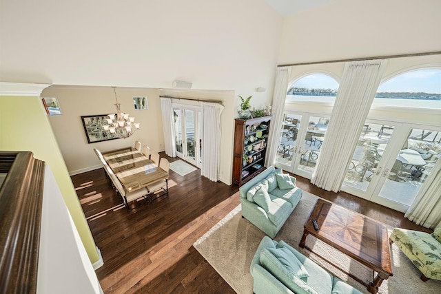 living area featuring a chandelier, french doors, a high ceiling, and dark wood-style flooring