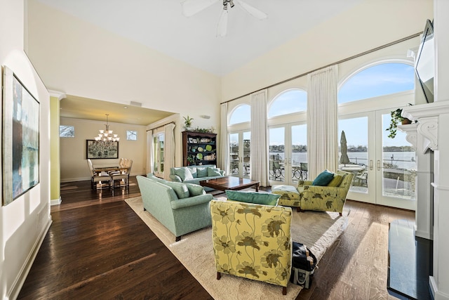 living room featuring baseboards, ceiling fan with notable chandelier, french doors, a towering ceiling, and hardwood / wood-style flooring