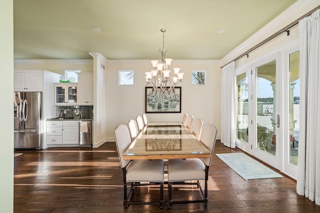 dining space featuring baseboards, dark wood-type flooring, an inviting chandelier, and ornamental molding