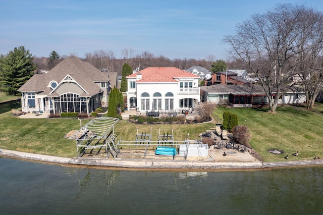 rear view of property featuring a balcony, a yard, and a water view