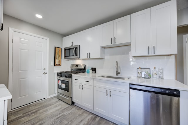 kitchen with white cabinets, sink, light wood-type flooring, and stainless steel appliances