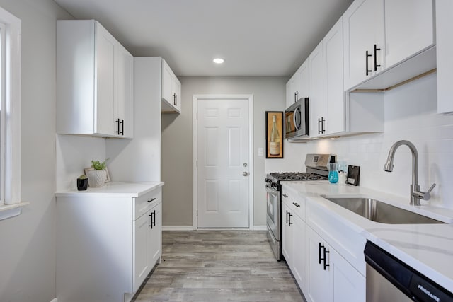 kitchen featuring white cabinetry, sink, stainless steel appliances, and light wood-type flooring