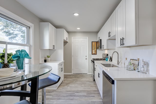 kitchen with stainless steel appliances, white cabinetry, and sink