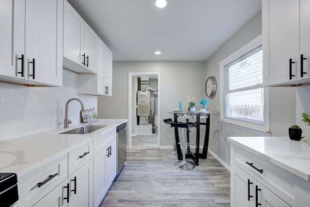 kitchen with light stone counters, sink, light hardwood / wood-style flooring, dishwasher, and white cabinets