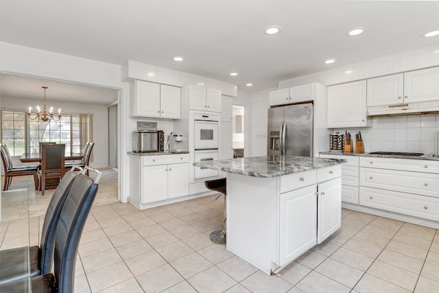 kitchen featuring dark stone counters, hanging light fixtures, a notable chandelier, a kitchen island, and stainless steel fridge with ice dispenser