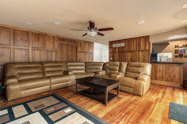 living room with ceiling fan, light hardwood / wood-style floors, and a textured ceiling