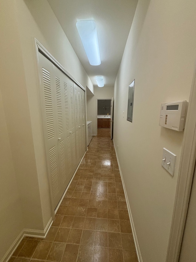 hallway featuring electric panel and baseboards