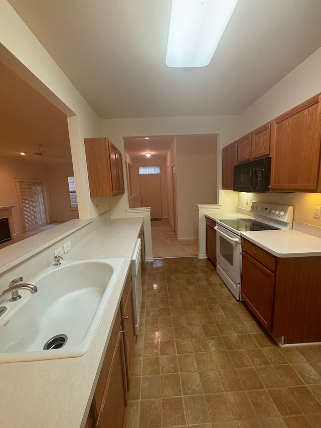 kitchen featuring brown cabinets, light countertops, electric range, a sink, and black microwave