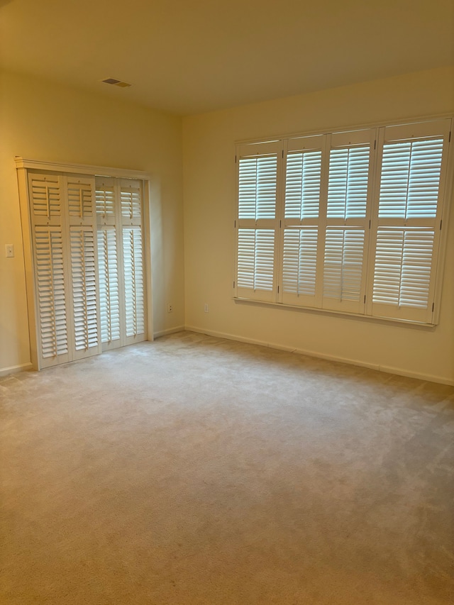 empty room featuring visible vents, carpet flooring, and a wealth of natural light