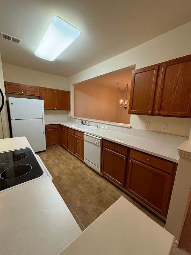 kitchen featuring brown cabinets, light countertops, visible vents, a sink, and white appliances