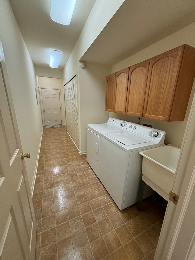 laundry area featuring cabinet space, baseboards, washer and clothes dryer, and a sink