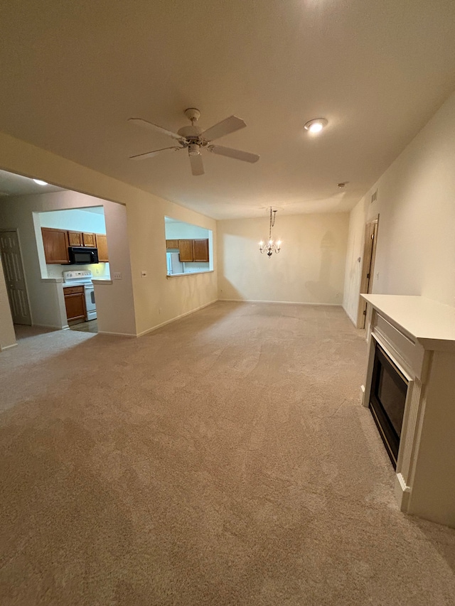 unfurnished living room featuring a glass covered fireplace, light carpet, baseboards, and ceiling fan with notable chandelier