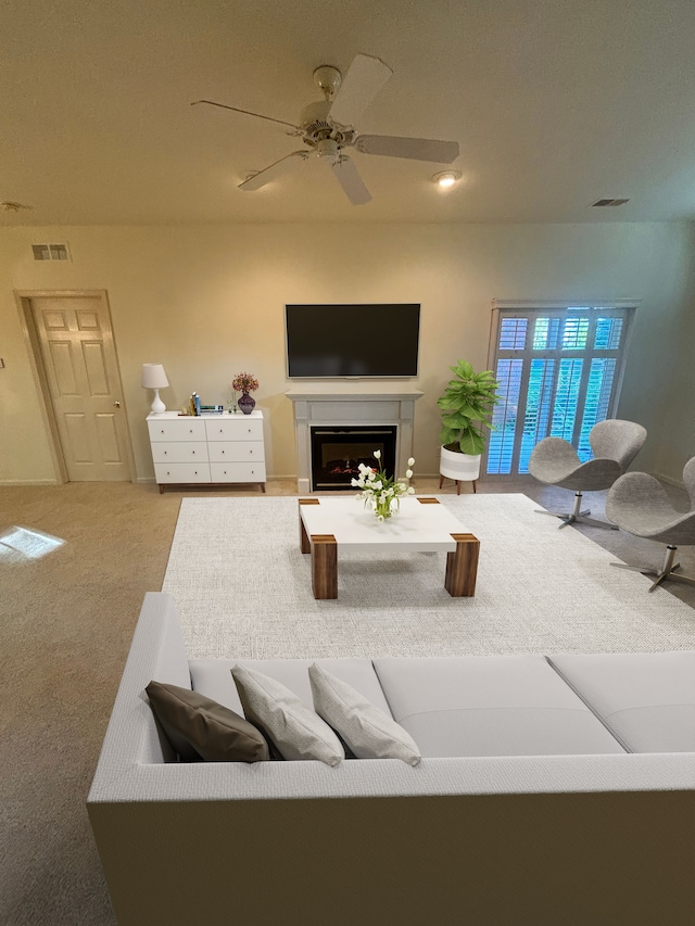 carpeted living area with visible vents, a fireplace, and ceiling fan