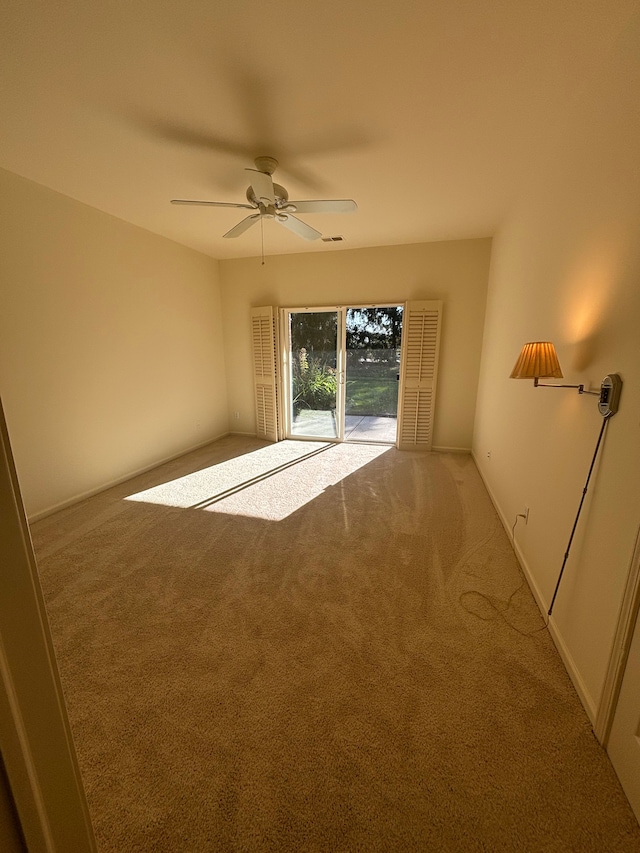 empty room featuring baseboards, visible vents, a ceiling fan, and carpet flooring