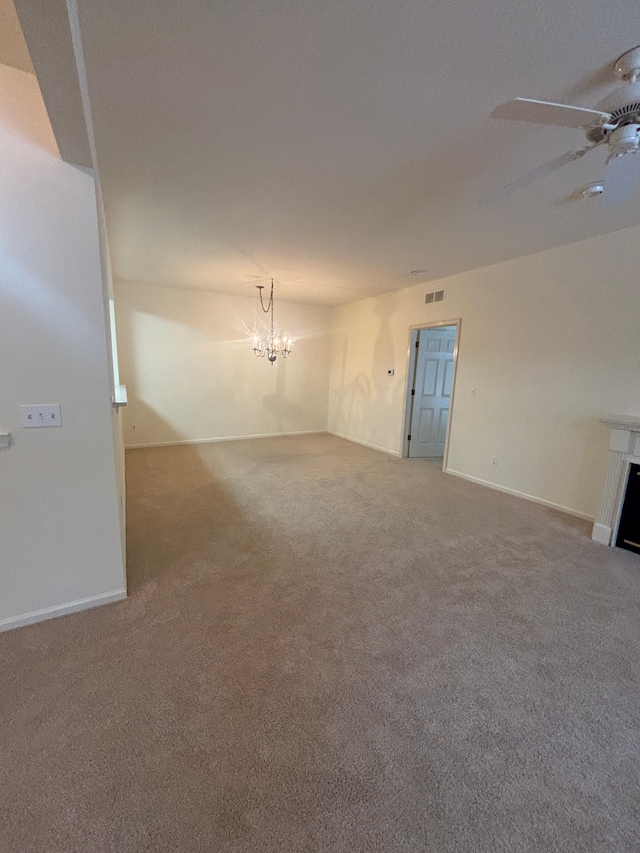 unfurnished living room featuring carpet floors, a fireplace, visible vents, baseboards, and ceiling fan with notable chandelier